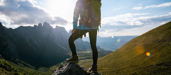 Woman backpacker hiking on sunset alpine mountain top