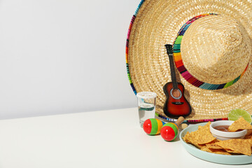 Nachos with sombrero and tequila on a light background