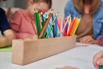 Colorful pencils and children drawing in the background