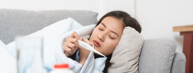 Woman measuring temperature her body on the bed. person got fever lying on the sofa.