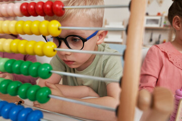 Preschool boy using abacus at kindergarten