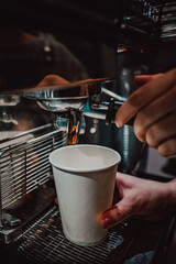 Close-up shot of coffee being poured into a white cup from an espresso machine, capturing the rich...