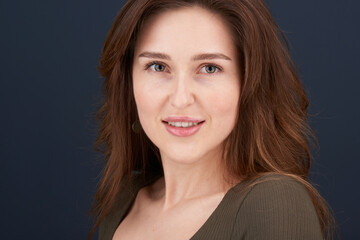 A close-up portrait of a beautiful young woman with pearly white teeth and green eyes