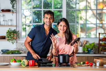 Indian young husband wife preparing food in the kitchen