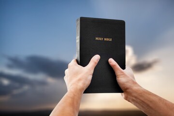 Open bible book in hands of person outdoor