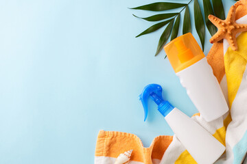 Vibrant flat lay photo of featuring sunscreen, towel, and seashell on a blue background, offering ample space for adverts or text - obrazy, fototapety, plakaty
