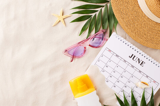 Summer vacation setup, top view of beach gear and calendar on sand texture with space for text