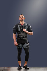 Full portrait of young confident man dressed in special suit for EMS workout, Modern training: Electro muscle stimulator on male model, great for gym equipment ads