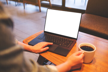 Mockup image of a woman using and working on laptop computer with blank white desktop screen while drinking coffee - 792602062