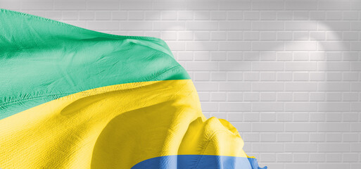 Gabon national flag cloth fabric waving on beautiful bricks Background.	
