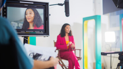 Vibrant On-set Image Of A Young Black Female Host In A Pink Suit, Engaging In A Lively Discussion...