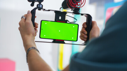 Close-up Of Young Caucasian Male Cinematographer Using Smartphone With Green Screen Mounted On...