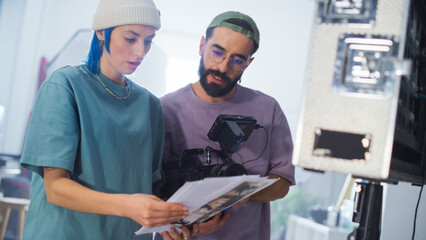 Young Caucasian Female And Middle Eastern Male Cinematographers Review A Script By A Camera On A...