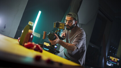 Focused Male Cinematographer With Beard, Wearing Cap And Glasses, Records Vibrant Scene On...