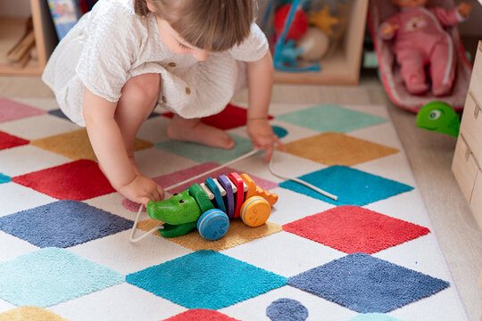 Toddler playing with a colorful wooden toy on patterned rug