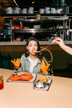 Woman in gloves eating with excitement at a diner