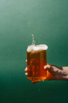 Hand holding a glass of refreshing light beer with foam