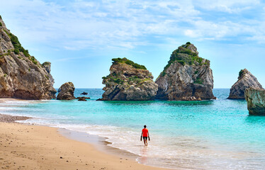 Woman walking at the stunning beach of the Praia do Ribeiro do Cac´valo, maybe the must beautiful...