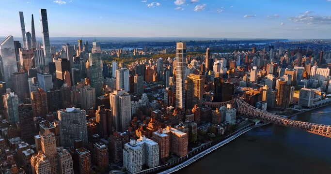 Setting sun lighting the facades of skyscrapers and high-rise buildings in New York downtown. Drone footage above the East River showing the part of the Queensboro bridge.