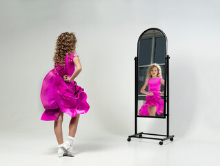 girl in a ballroom dancing dress admires herself in the mirror by moving her dress