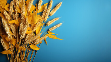 Obraz premium Golden wheat and leaves against a vibrant blue background