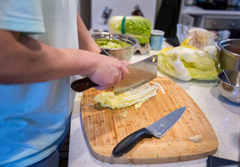 Man chopping Chinese cabbage in the home kitchen.
