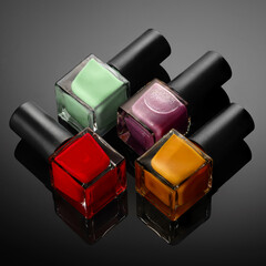 Nail polish Bottles of bright colors on a dark background with reflections.