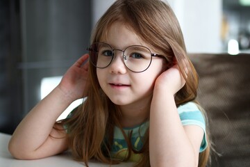 Portrait of a cute little girl big with glasses smiling in a school setting - 792622873