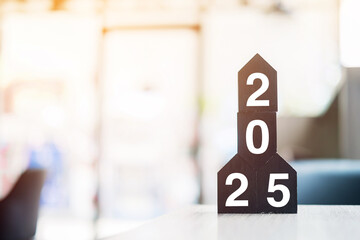 2025 Happy New Year with wooden Home model on table office. New House, Financial, Property...