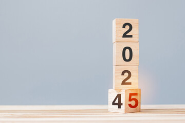 2024 chang to 2025 wooden cube blocks on table background. Resolution, plan, review, goal, start,...
