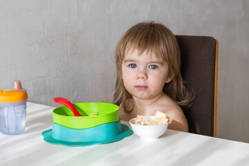 Young girl with serious expression sitting at table and enjoying her meal - 792623644