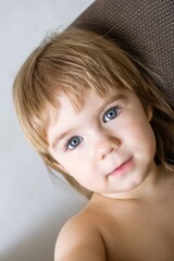 Portrait of a cute little blonde girl with blue eyes smiling at the camera - 792624090