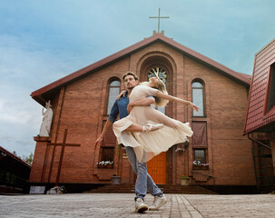 partner in love on a summer day circles a ballerina on the street in front of a church