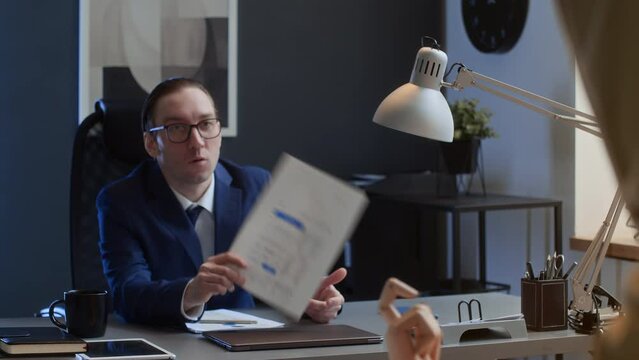 Medium shot of male office worker searching for missing presentation page on desk, nasty colleague holding document up, taunting and teasing him