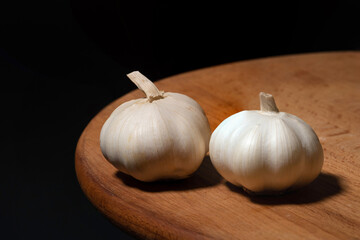 Garlic on a wooden kitchen board on a black background. Organic garlic - 792632217