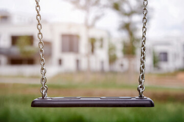 Swing on Residential Buildings Background. Empty Swing Seat. Playground Child's Swing without...