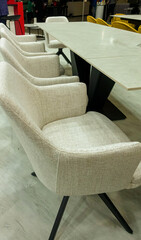 Classic armchairs upholstered in gray fabric stand behind a long table.