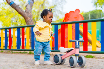 African baby girl in a playground with a toy bike