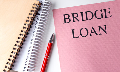 BRIDGE LOAN text on pink paper with notebooks