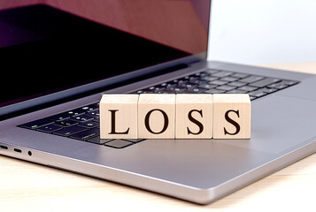 LOSS word on wooden block on laptop , business concept