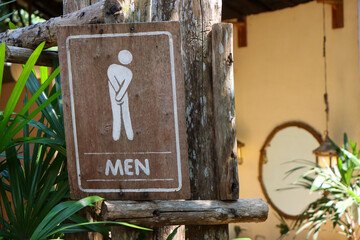 Selective focus: Men's restroom sign decorated with shady trees in front of a restroom in a cafe in the forest in Thailand.