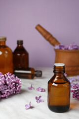 Lilac essential oil. Spa oil with lilac flowers. Bottle with aroma oil and lilac flowers on marble...