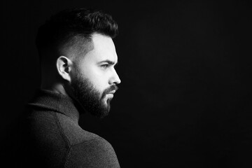 Portrait of handsome bearded man on dark background, space for text. Black and white effect