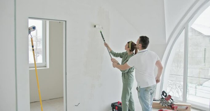 Couple engages in a home renovation project, painting the interior walls of their new apartment. Transforming their living space with paint. This captures a moment of teamwork and domestic improvement