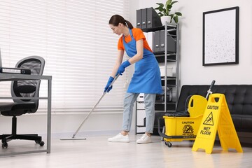 Cleaning service. Woman washing floor with mop in office