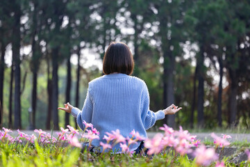 Asian woman is doing meditation mudra in forest with spring bulb flower in blooming season for...