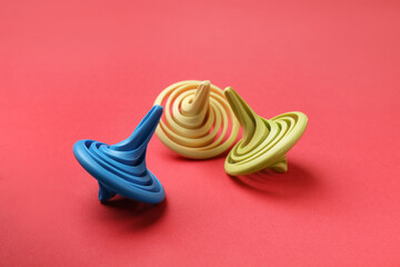 Many colorful spinning tops on red background, closeup
