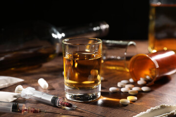 Alcohol and drug addiction. Whiskey in glass, syringes, pills and cocaine on wooden table - obrazy, fototapety, plakaty