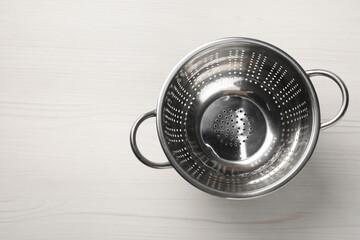 Metal colander on white wooden table, top view. Space for text