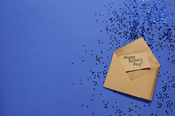 Card with phrase Happy Father's Day in envelope and confetti on blue background, top view. Space...